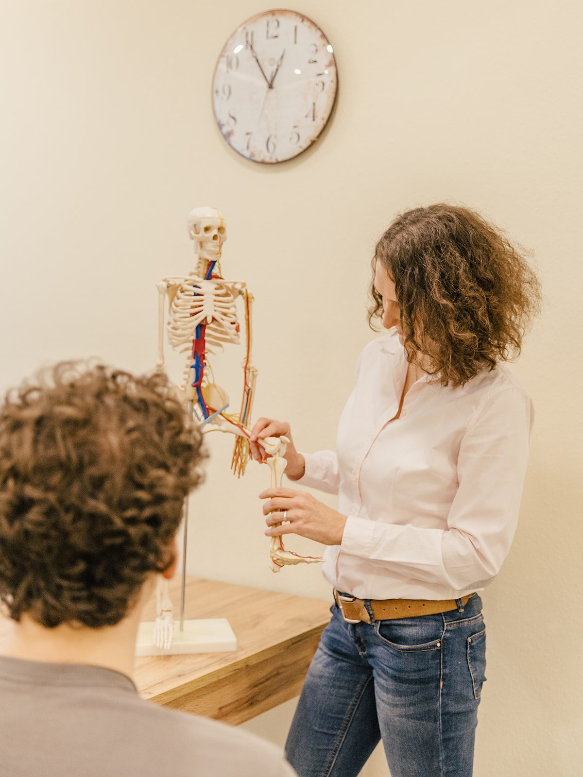 Sophie erklärt einem Patienten am Skelettmodell